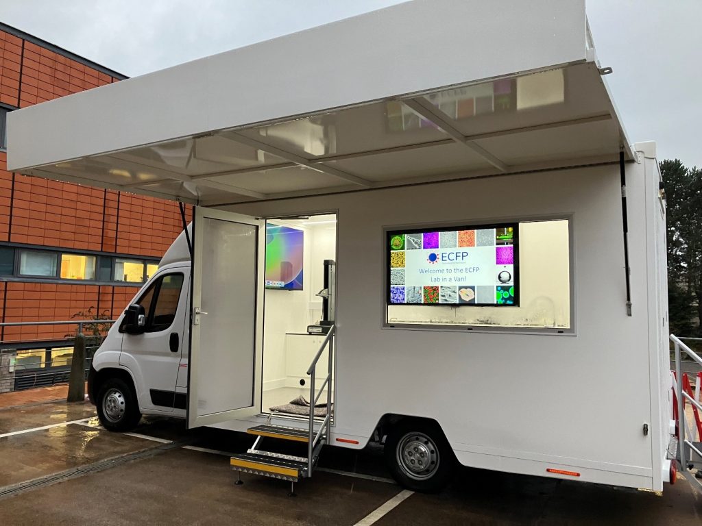 A white van with a side door and steps leading up to it.