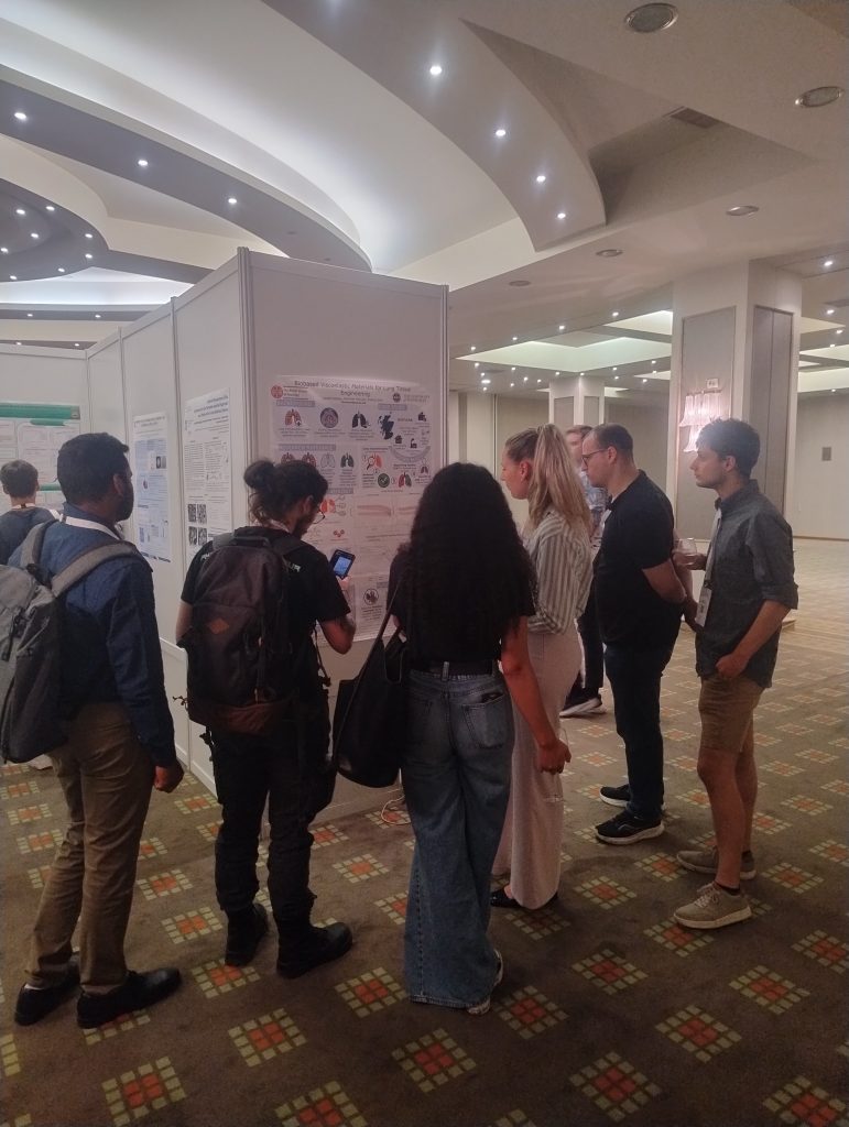 A group of conference attendees are shown reading a poster.