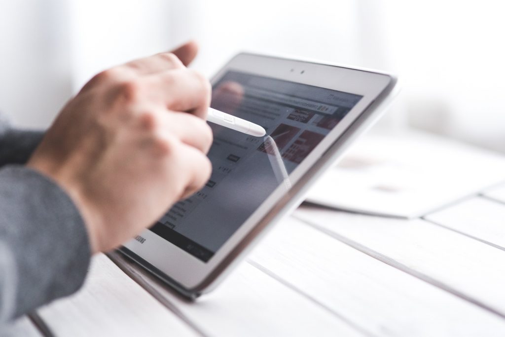 A person writes on a tablet screen using a stylus.